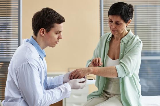 A woman shows a doctor her arm.